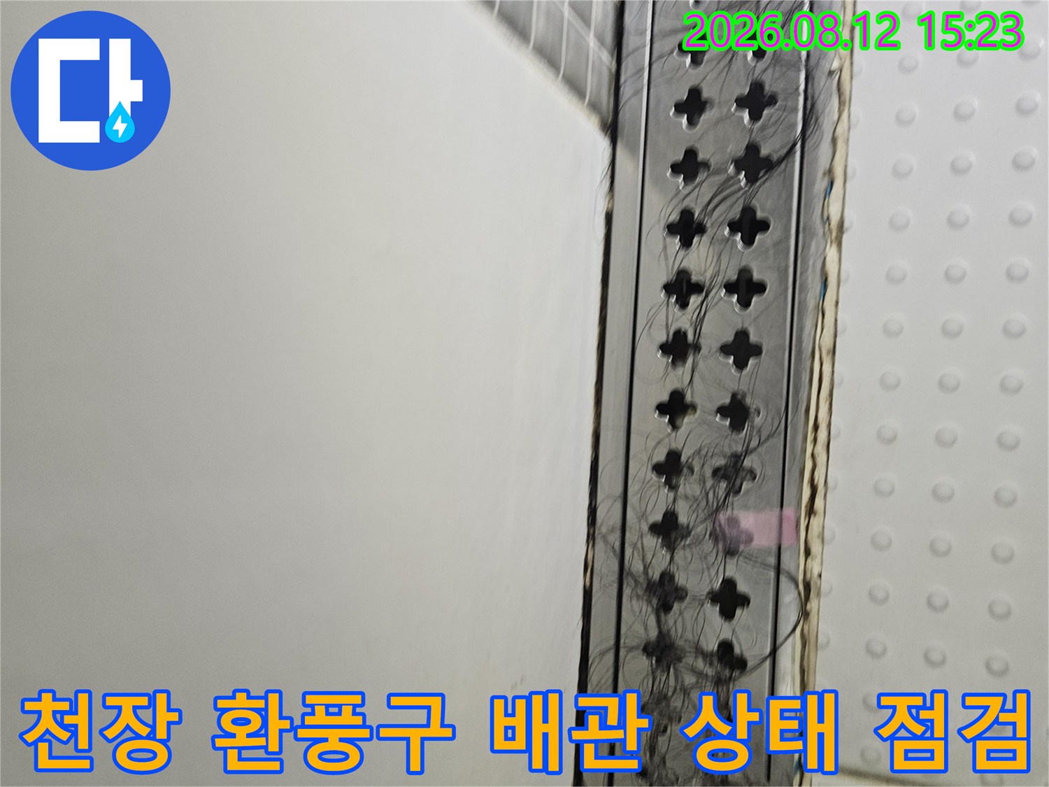 흰색 천장 마감재 아래에 위치한-격자무늬 환풍구와 복잡하게 얽힌 전선들