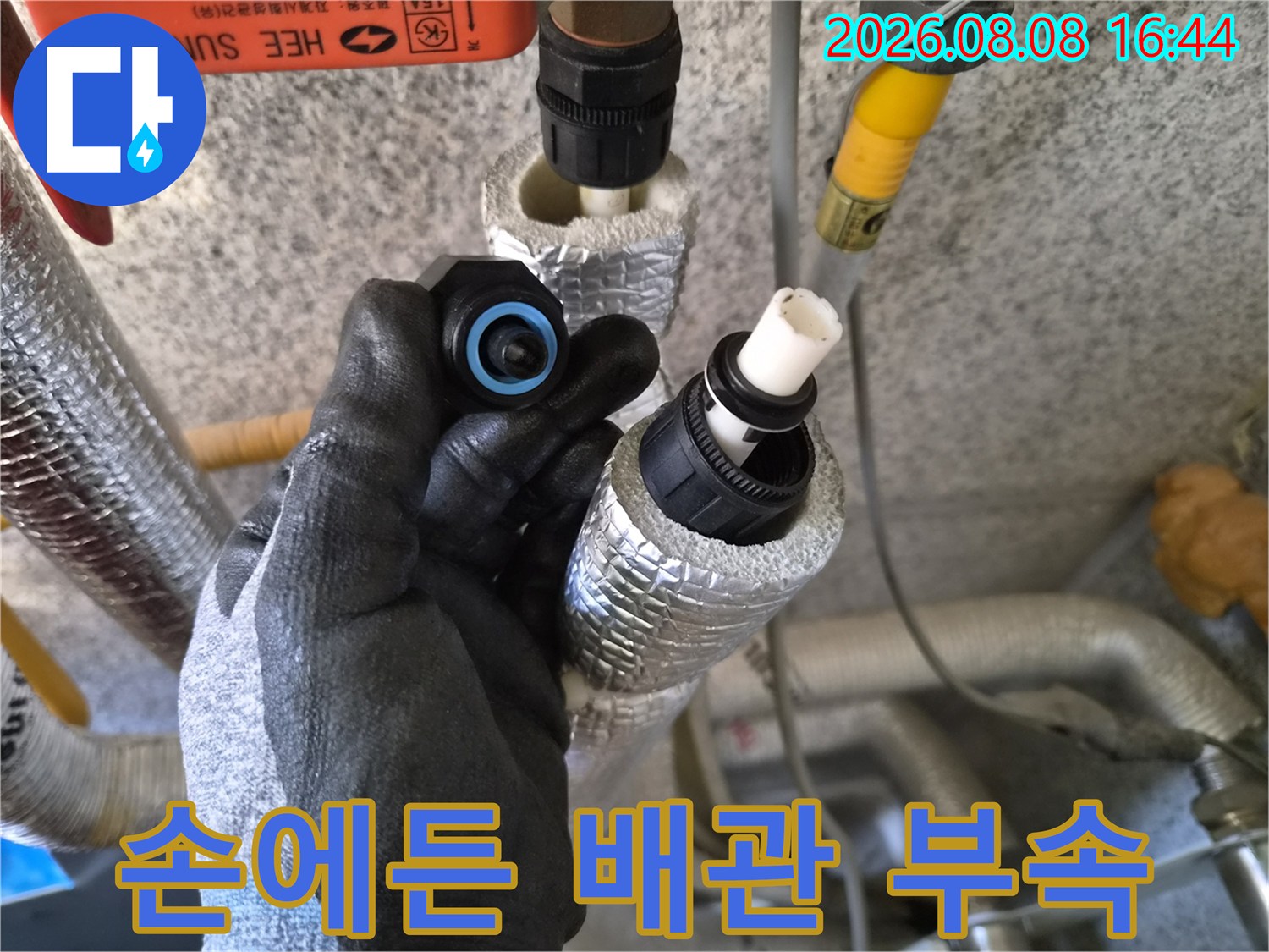작업자가 손에 들고 있는 검은색 배관 연결 부속과 분리된 배관 모습