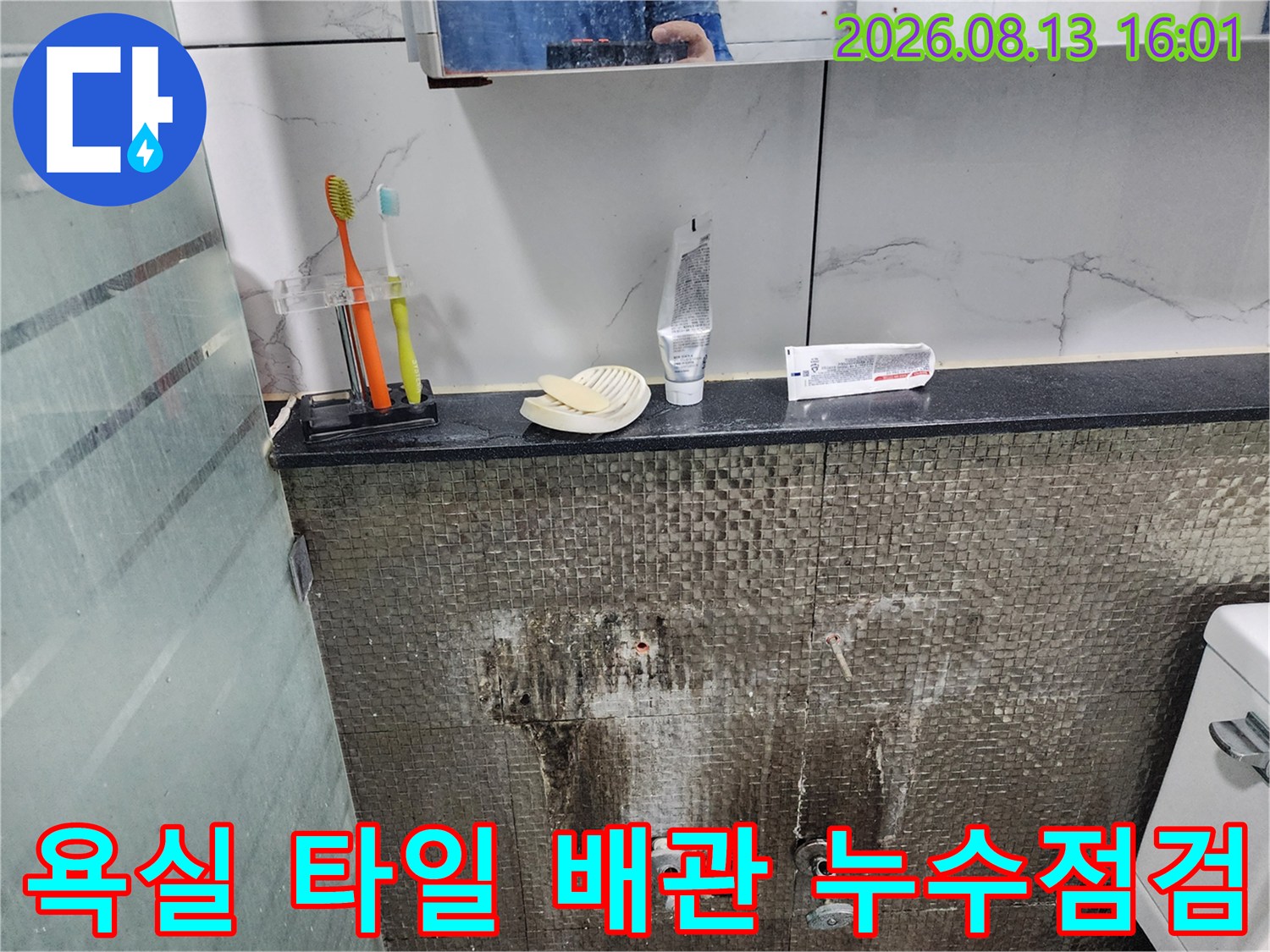 창동 화장실-수전 연결 부위 주변의 젖은 타일 표면과 얼룩진 벽면 모습입니다.