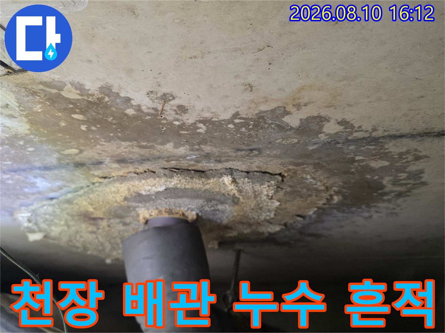 누수 피해를 입은 천장-배수관 주변에 넓게 퍼진 물 얼룩과 오염