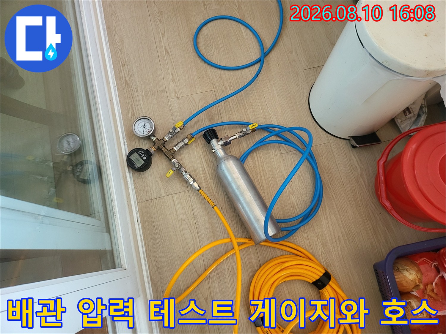 파란색 호스와 연결된 배관 압력 측정용 게이지 및 가스 주입 장치 이미지입니다.
