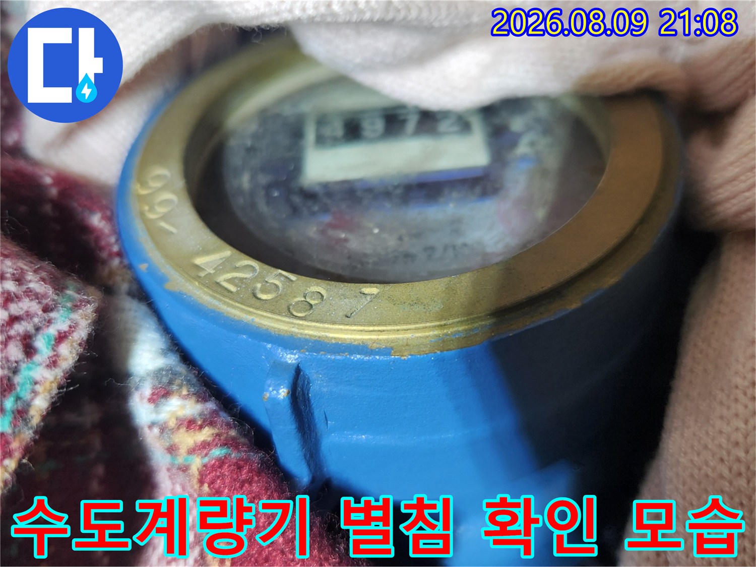 파란색 수도 계량기의 숫자판과 별침 부분을 근접 촬영한 사진