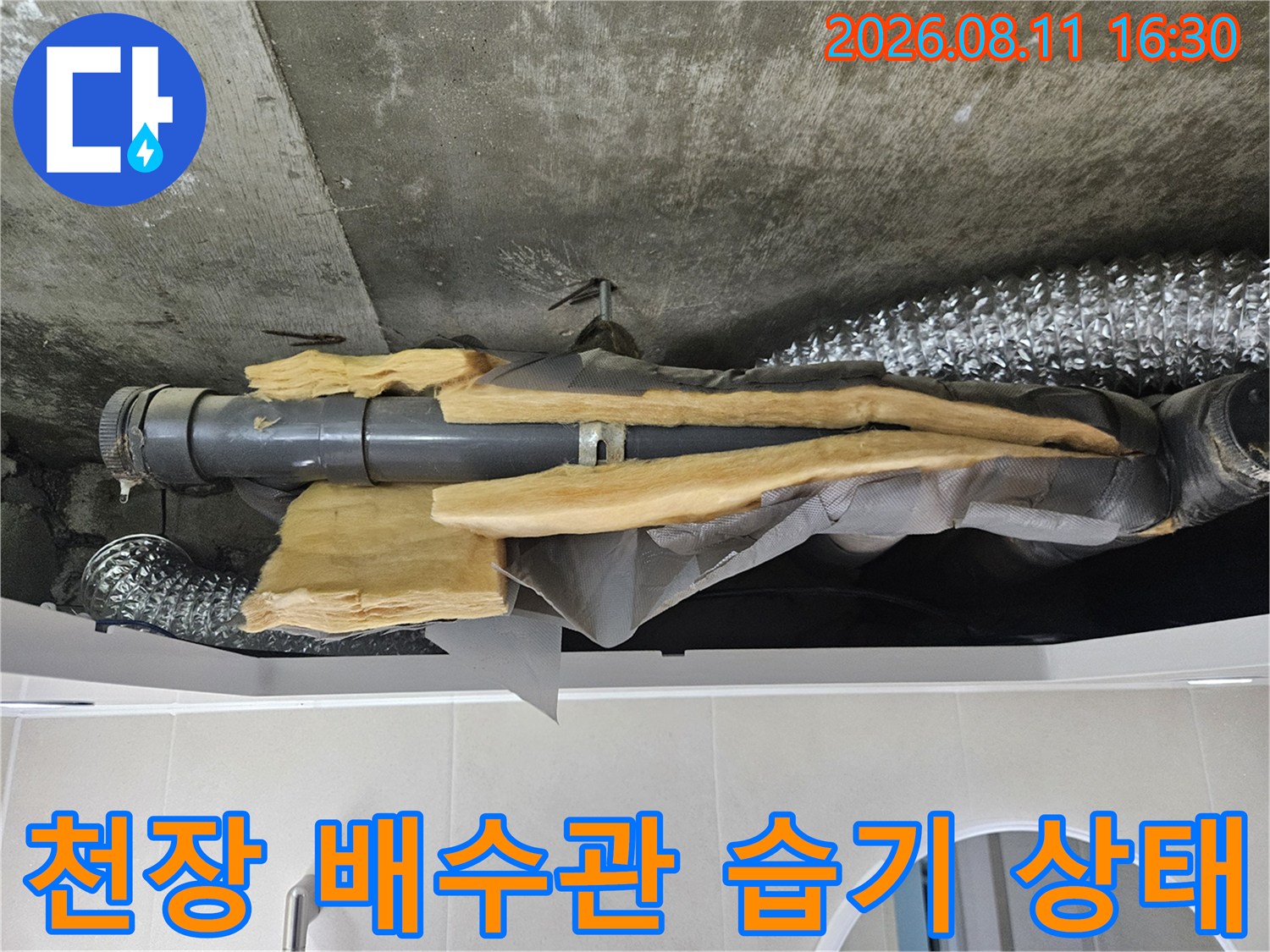 화장실 천장 내부-배관 주변의 젖은 콘크리트와 보온재 노출
