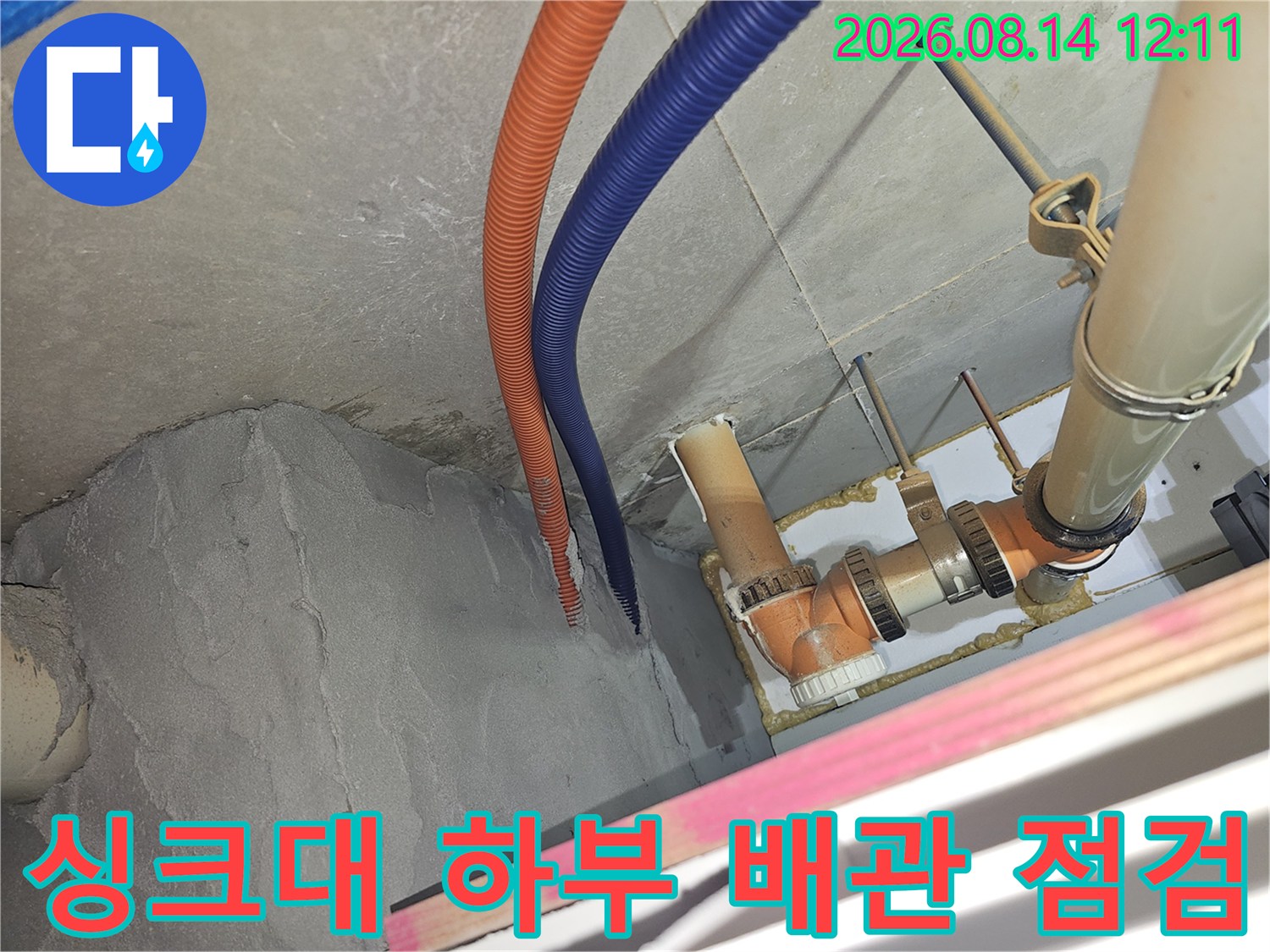 성남 분당구 아파트 싱크대 하부의 오렌지색과 파란색 주름관 및 PVC 배관 상태를 정밀하게 점검하는 모습입니다.