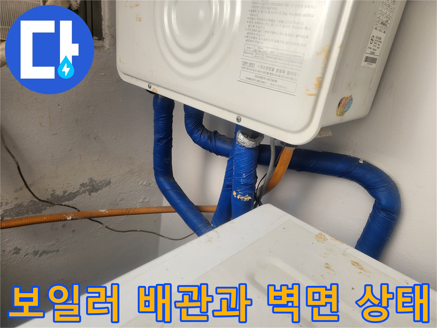 보일러 하부의 파란색 보온재로 감싸진 배관과 노후된 벽면 모습