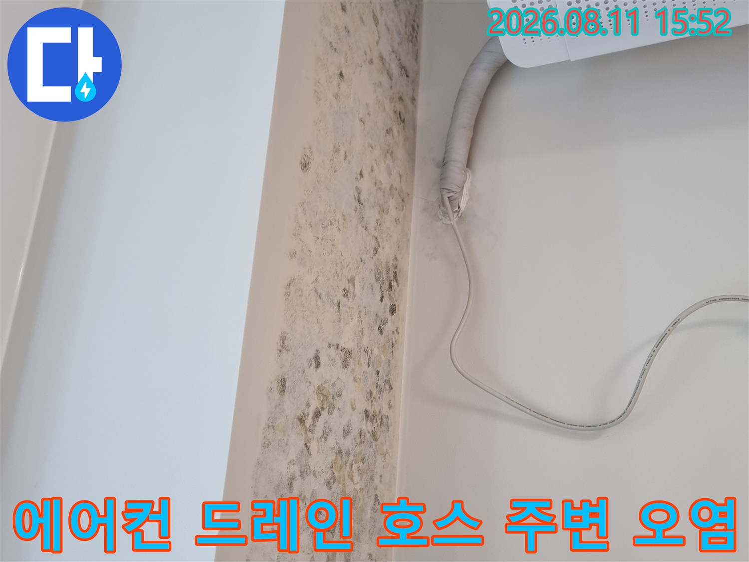 흰색 벽면에 발생한 불규칙한 갈색 얼룩과 에어컨 드레인 배관의 모습