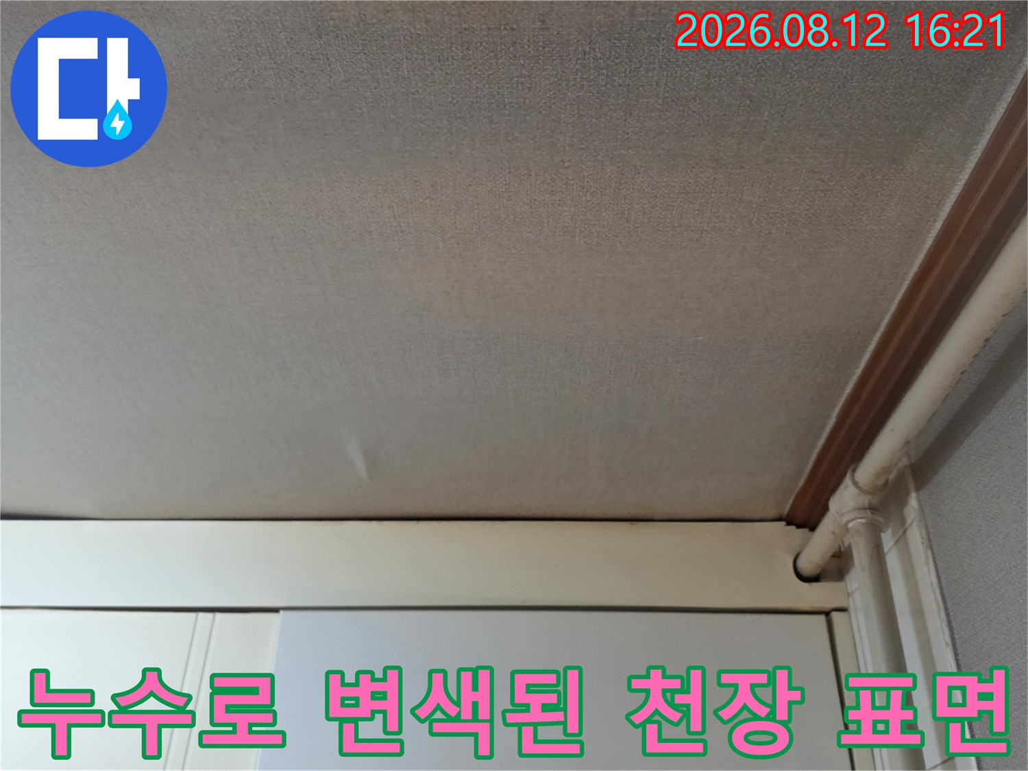 전체적으로 눅눅하게 젖어 색이 바랜 천장 벽지와 배관의 모습