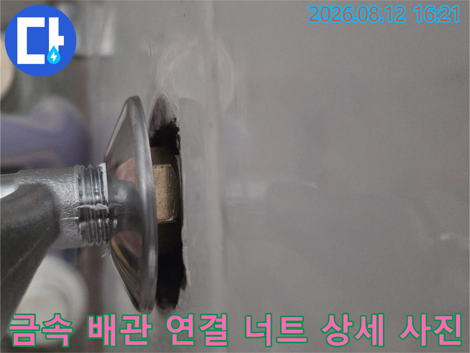 천장 구멍을 통해 보이는 은색 금속제 배관의 나사산과 연결 부위 모습