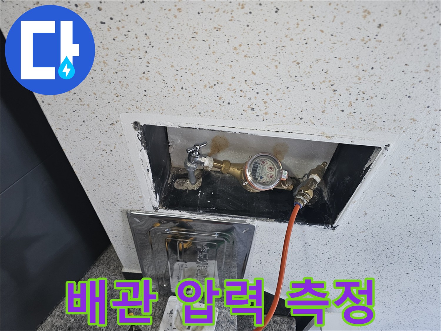 주황색 호스가 연결된 디지털 압력계와 수도 계량기