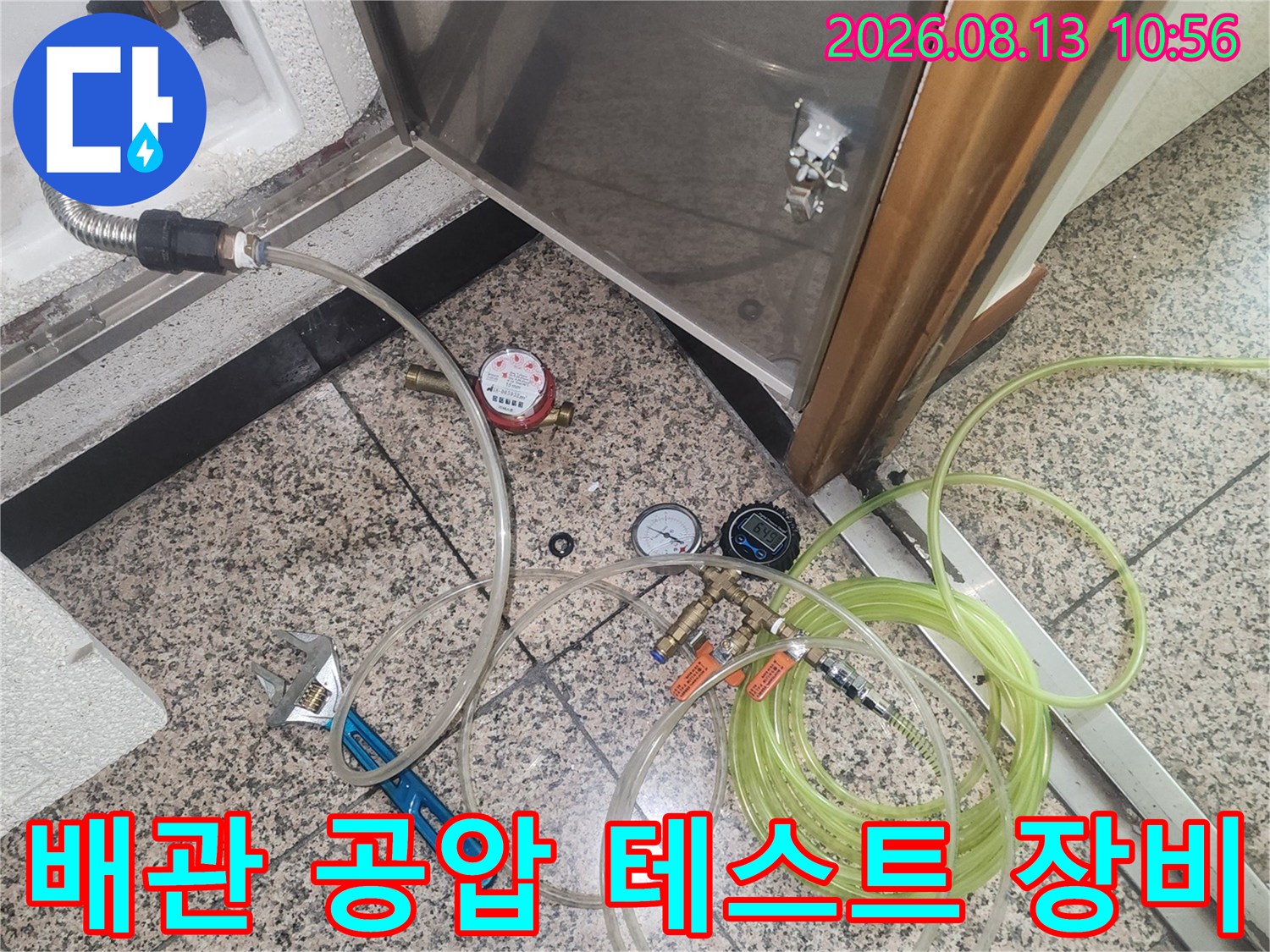 바닥 점검구 부근에 배치된 누수 탐지용 공압 측정기와 투명 호스-장비 세팅 모습