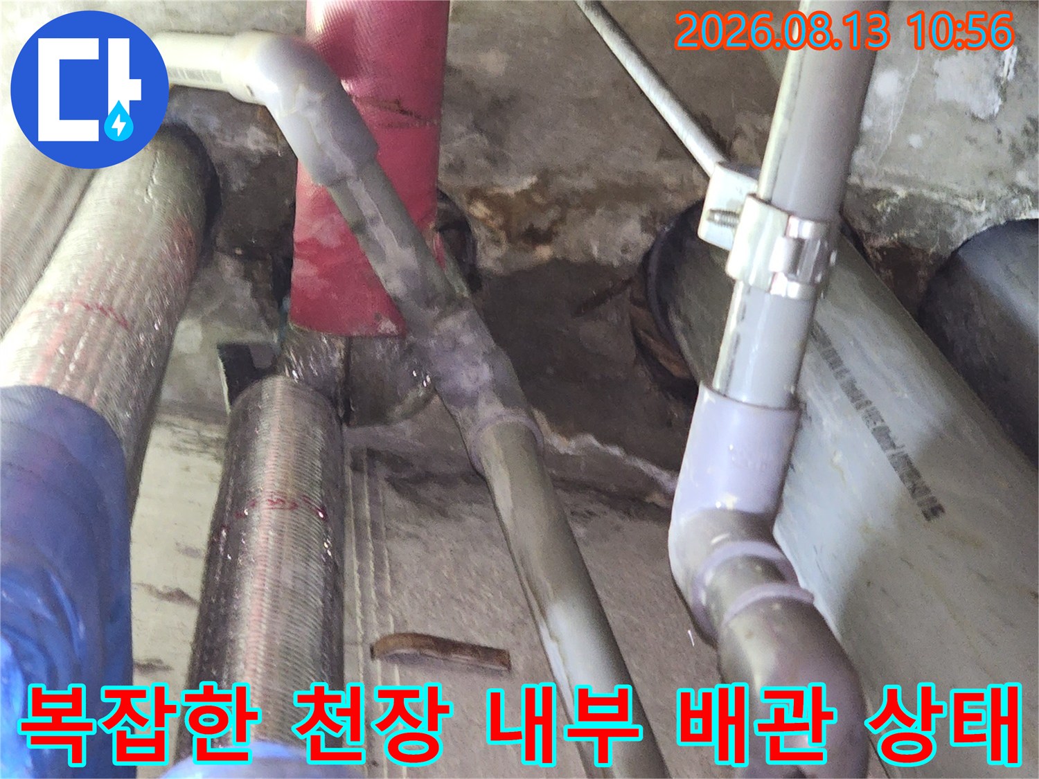 천장 속에 설치된 여러 종류의 회색과 빨간색 배관들이 얽혀 있는 모습