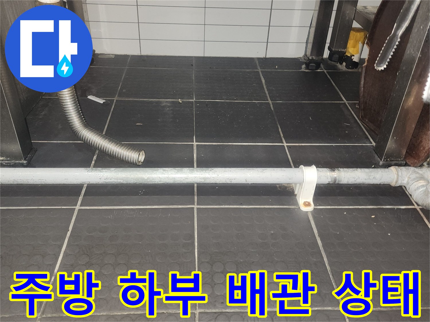 식당 주방 벽면의 수직 배관과 연결된 유연한 호스 부위입니다.