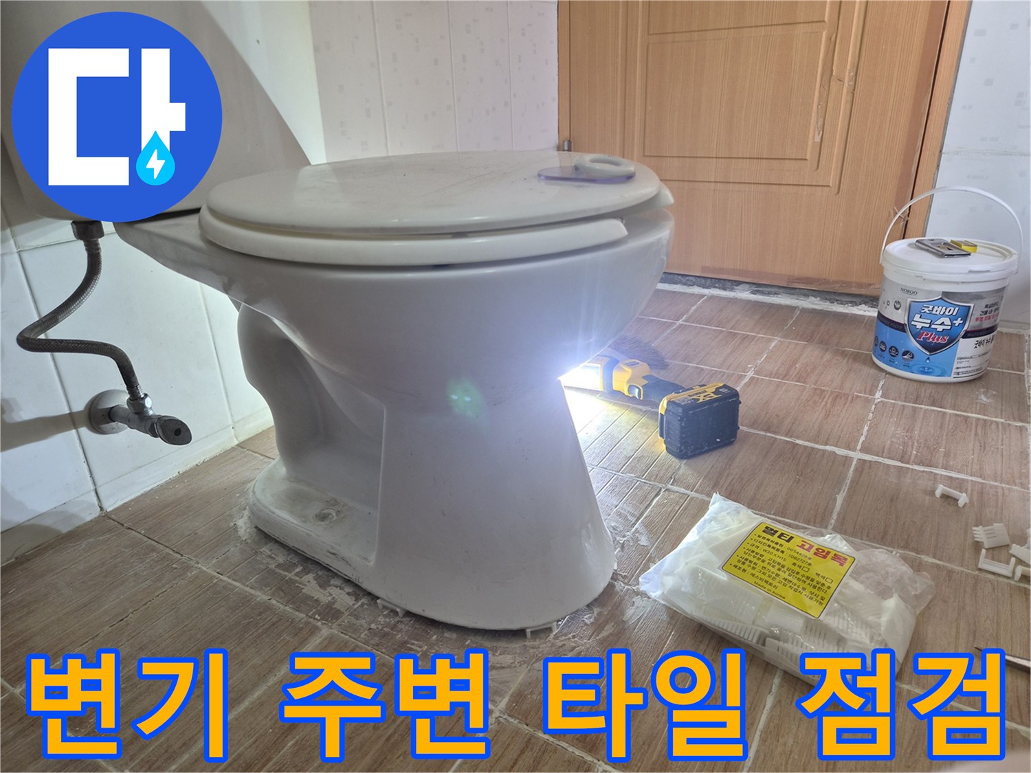 변기 아래쪽 젖은 타일과 작업 도구들의 모습