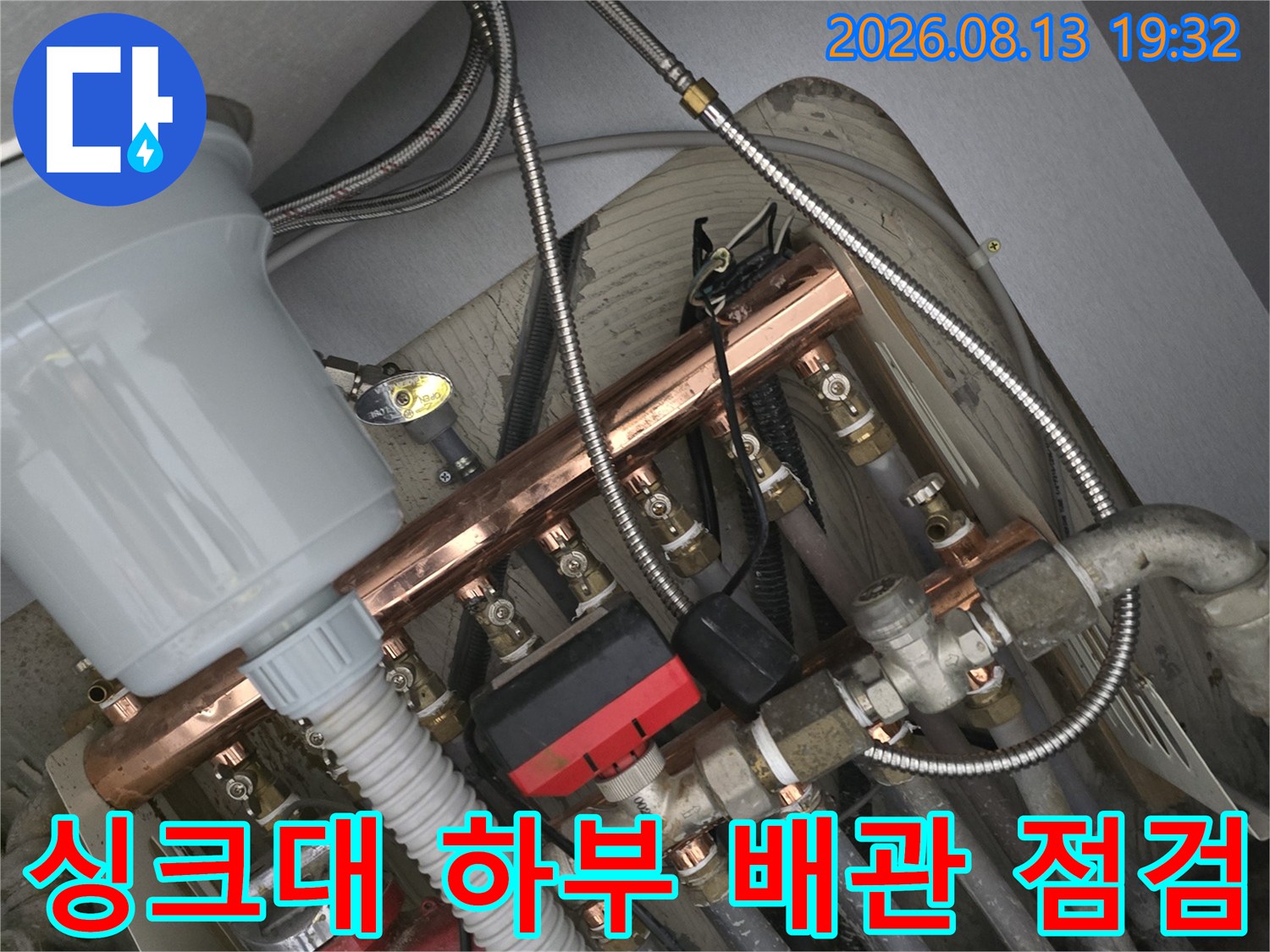 금속 분기 관과 호스가 연결된 싱크대 아래쪽 급수 계통의 상세 사진입니다.