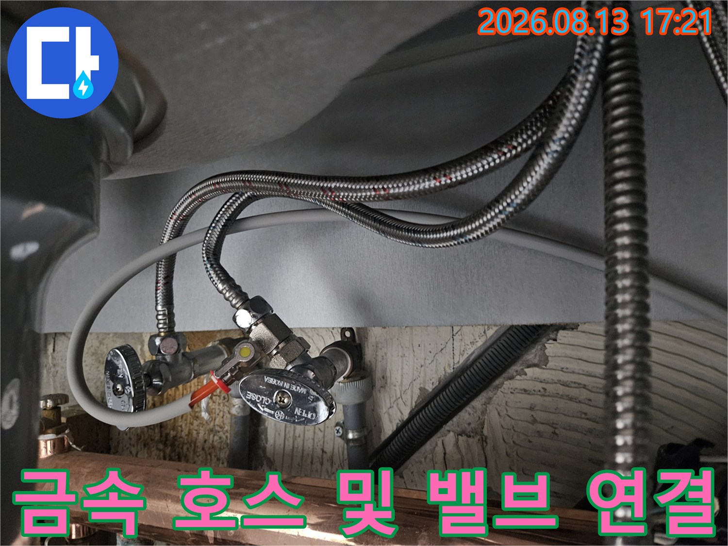 싱크대 하부의 은색 앵글밸브와 유연한 급수 호스 상세 모습