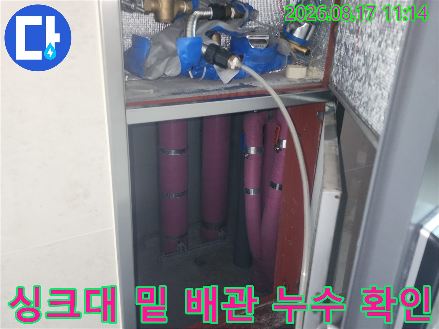 싱크대 하단부 금속 밸브와 분홍색 배수 호스의 습기 상태 점검