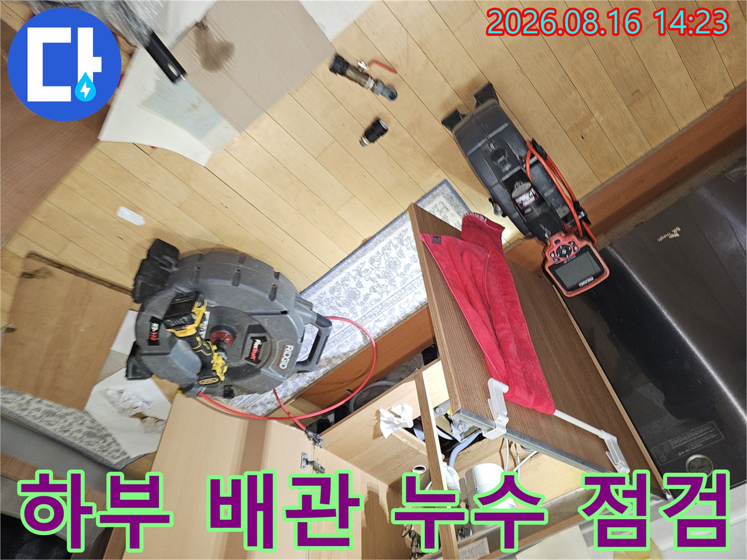 싱크대 하부 공간의 배관과 검사 장비를 배치한 현장 사진입니다.