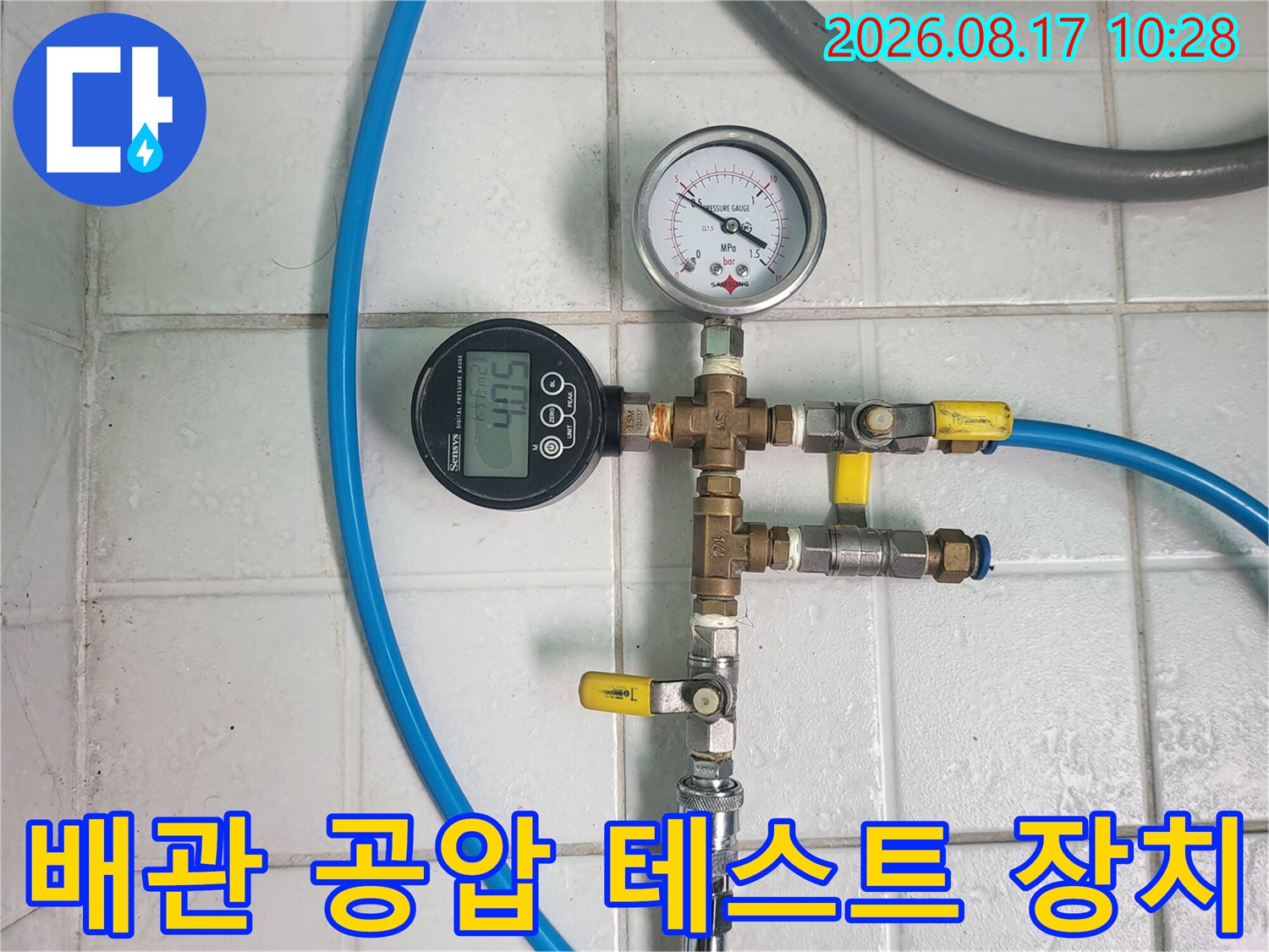 금속 배관 부속에 연결된 압력 측정 게이지와 호스 모습입니다.