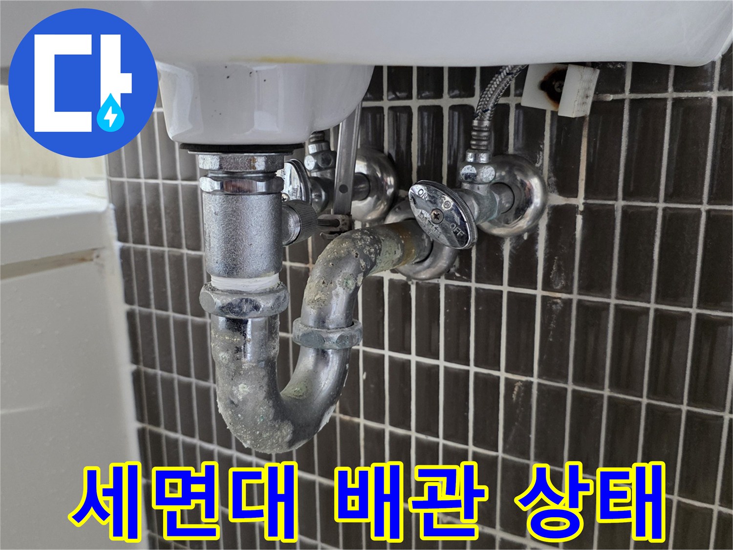 세면대 아래쪽 배수관 연결 부위와 타일 벽면 모습