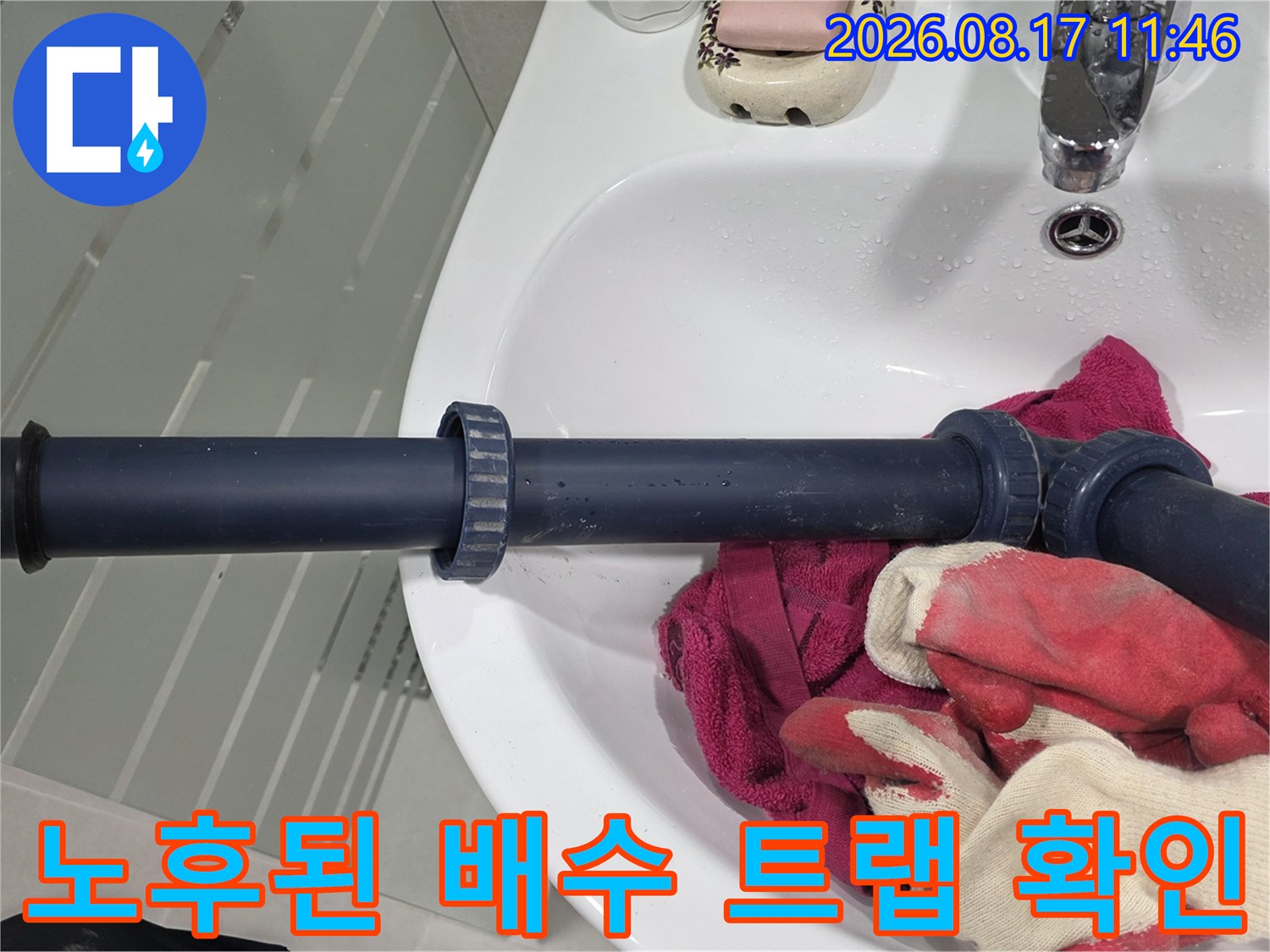 세면대 하단 짙은 색 배수 트립과 연결 부위의 상태를 근접 촬영함