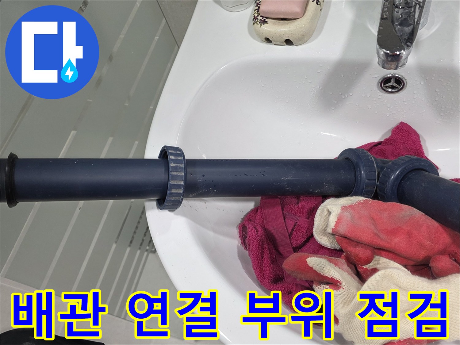 파란색 오배수관과 작업용 장갑이 놓인 화장실 내부 모습