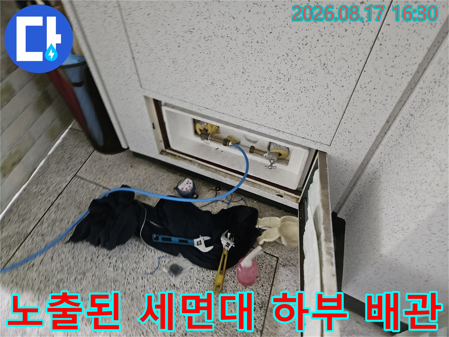 세면대 밑-점검 중인 수도 배관과 작업 도구들