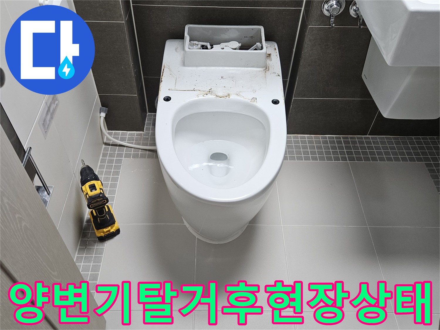 양변기가 제거된 화장실 바닥과 작업용 전동 드릴의 모습