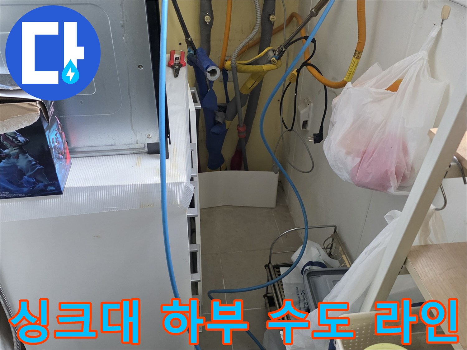 싱크대 아래쪽의 노란색 배관과 파란색 호스가 복잡하게 연결된 상태입니다.