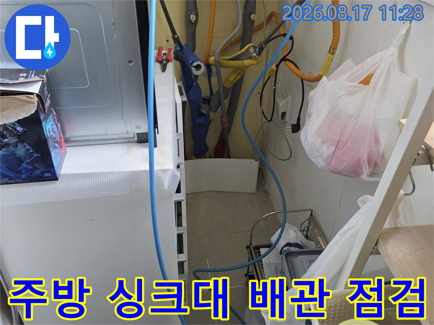 싱크대 아래쪽의 수도 밸브와 정수기 연결 호스들을 점검하는 현장 사진입니다.