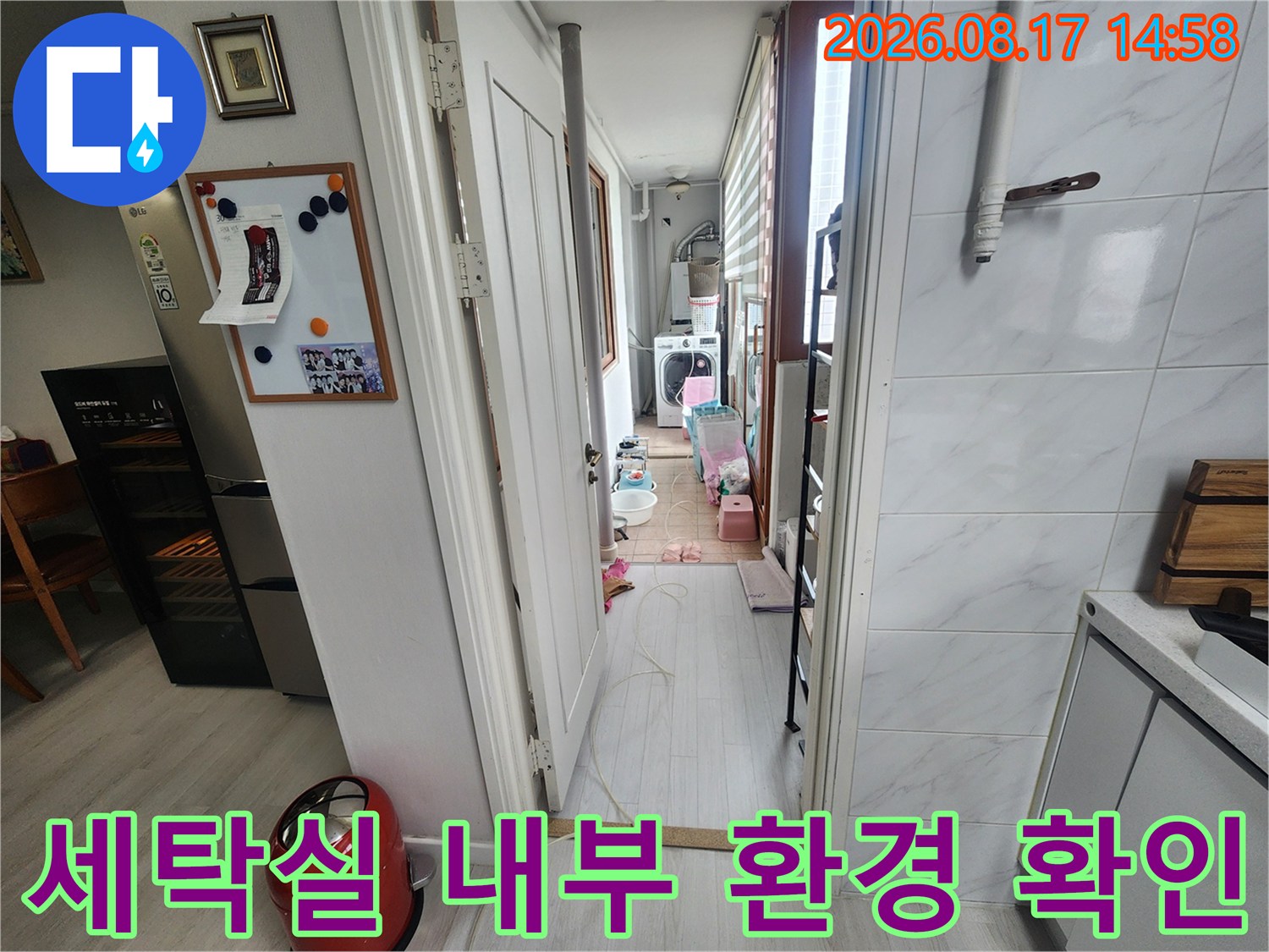 세탁기 가전과 복도 벽면이 보이는 아파트 내부 공간입니다.