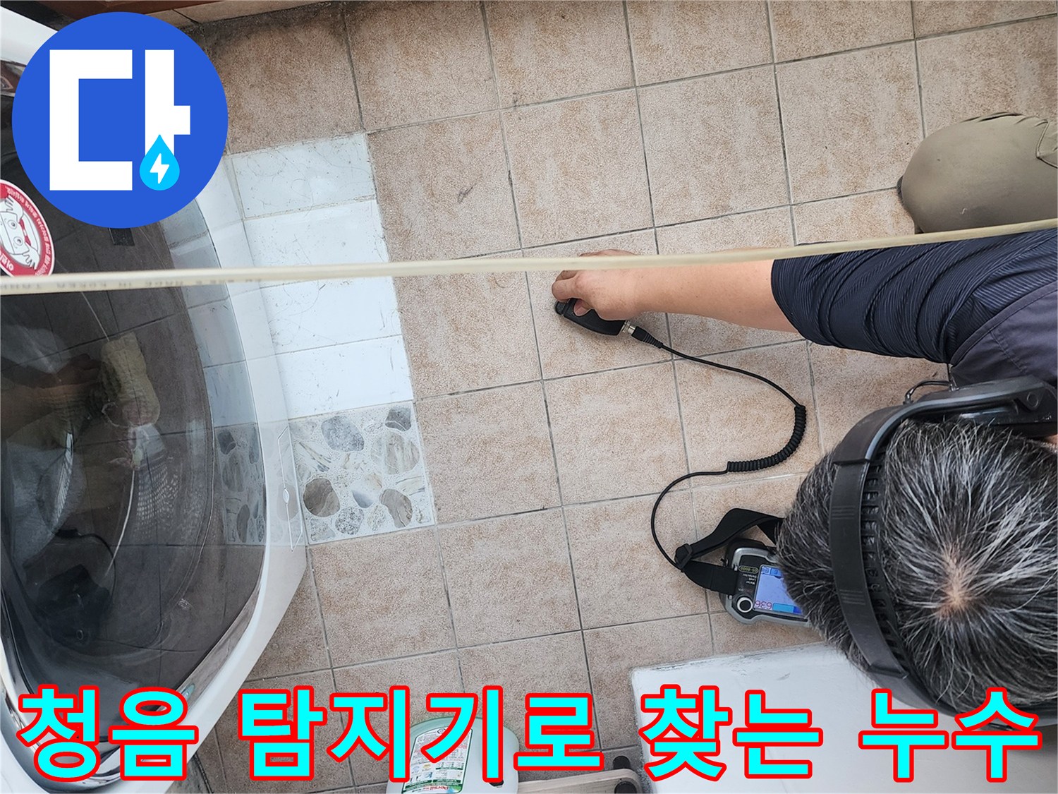 세탁실 바닥에서 청음식 누수 탐지기를 사용하여 배관의 미세한 물소리를 추적하는 모습입니다.