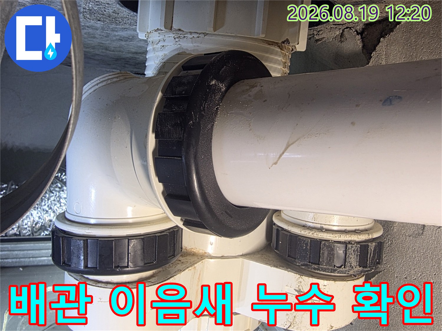 흰색 배관과 검은색 부속품-배관 연결 부위의 누수 여부를 점검하는 모습입니다.