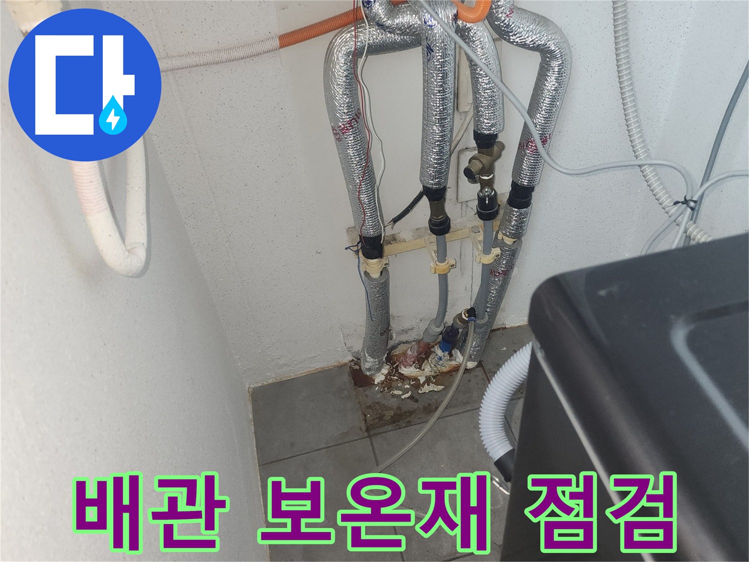 보온재로 덮인 배관과 세탁기 연결 호스가 보이는 보일러실 내부 모습입니다.