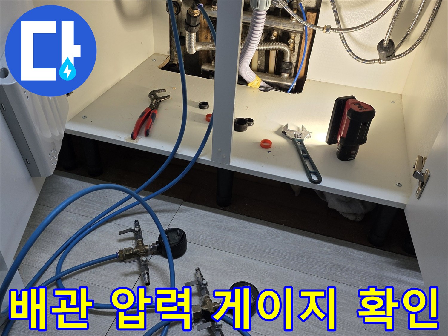 보일러 하단 배관에 연결된 파란색 호스와 압력계
