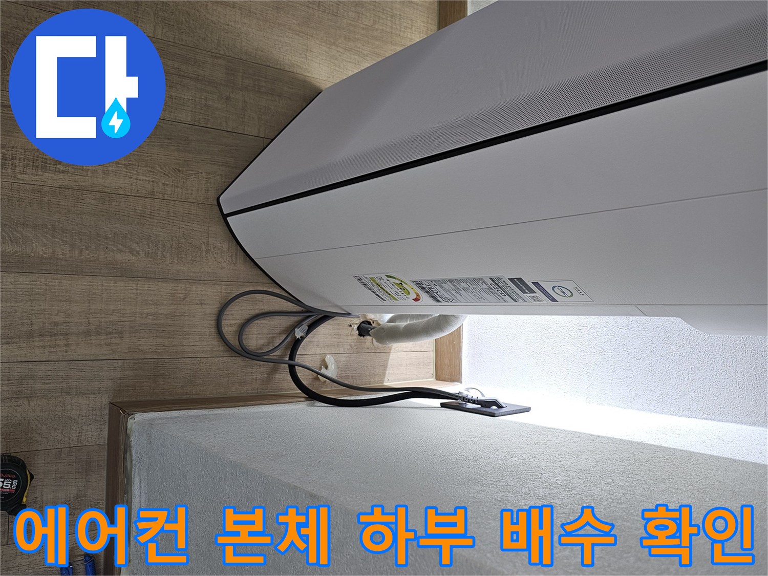 에어컨 기기 하단에서 나오는 드레인 호스의 연결 상태를 보여줍니다.