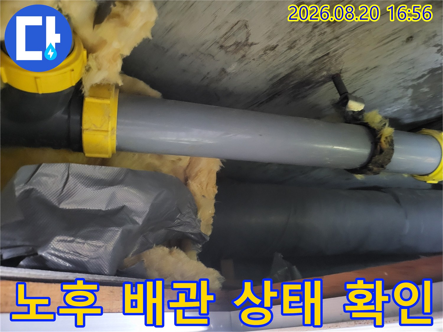 천장 내부의 회색 배관과 젖어있는 유리섬유 단열재를 촬영한 사진입니다.