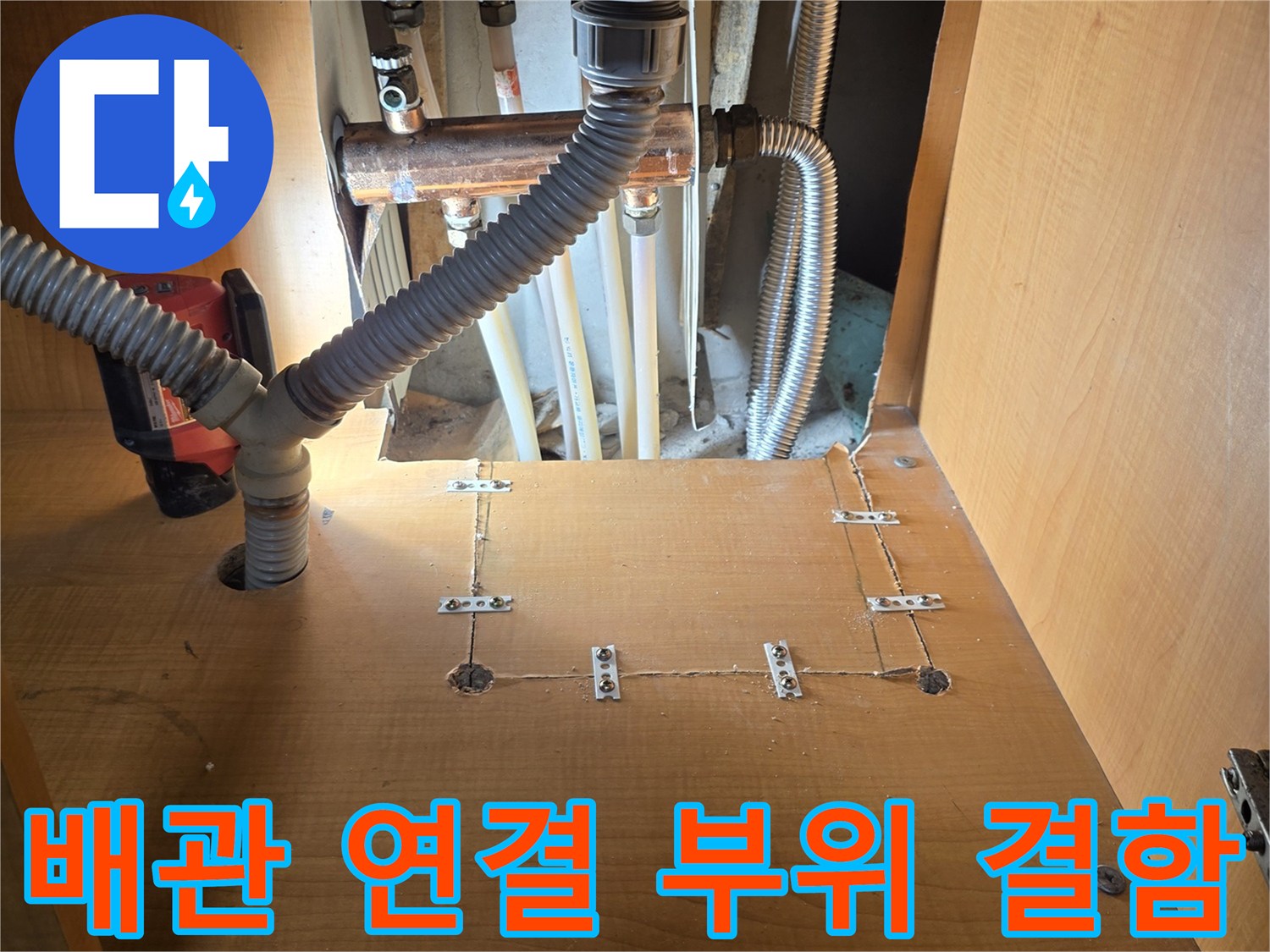 싱크대 하부장 내부의 금속 배관과 주름관 접합부 상세 사진