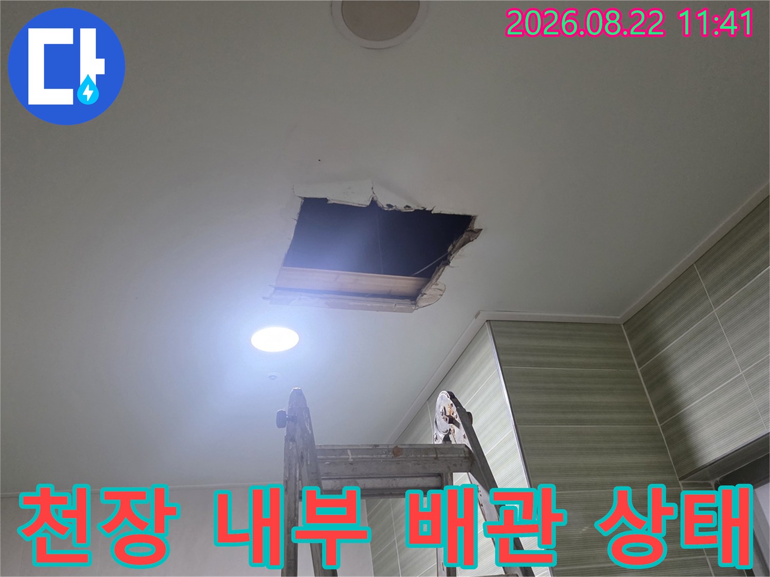 열린 점검구-천장 안쪽의 배관과 구조물을 확인하고 있습니다.
