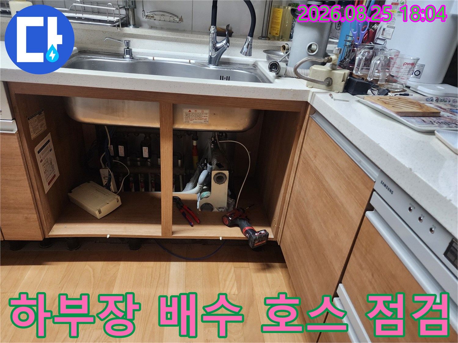싱크대 하단 수납장 내부의 배수 호스와 각종 연결 부위 노출 상태