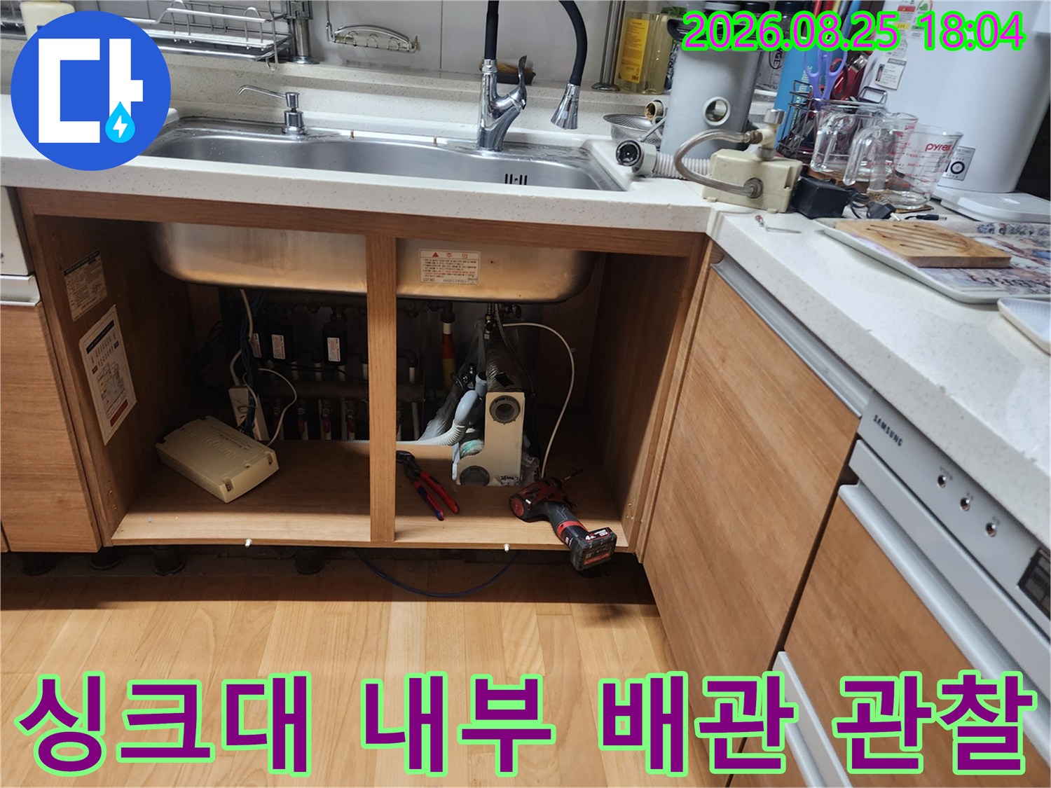 주방 싱크대 하부 수납공간 내부에 노출된 배수 시설과 연결 부위 점검 중