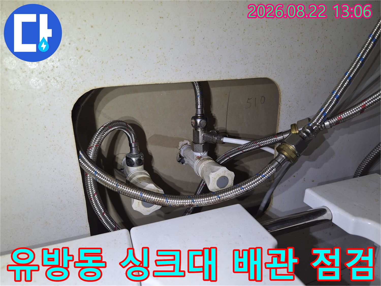 싱크대 하부의 금속 호스와 밸브 연결 부위를 근접 촬영한 사진입니다.