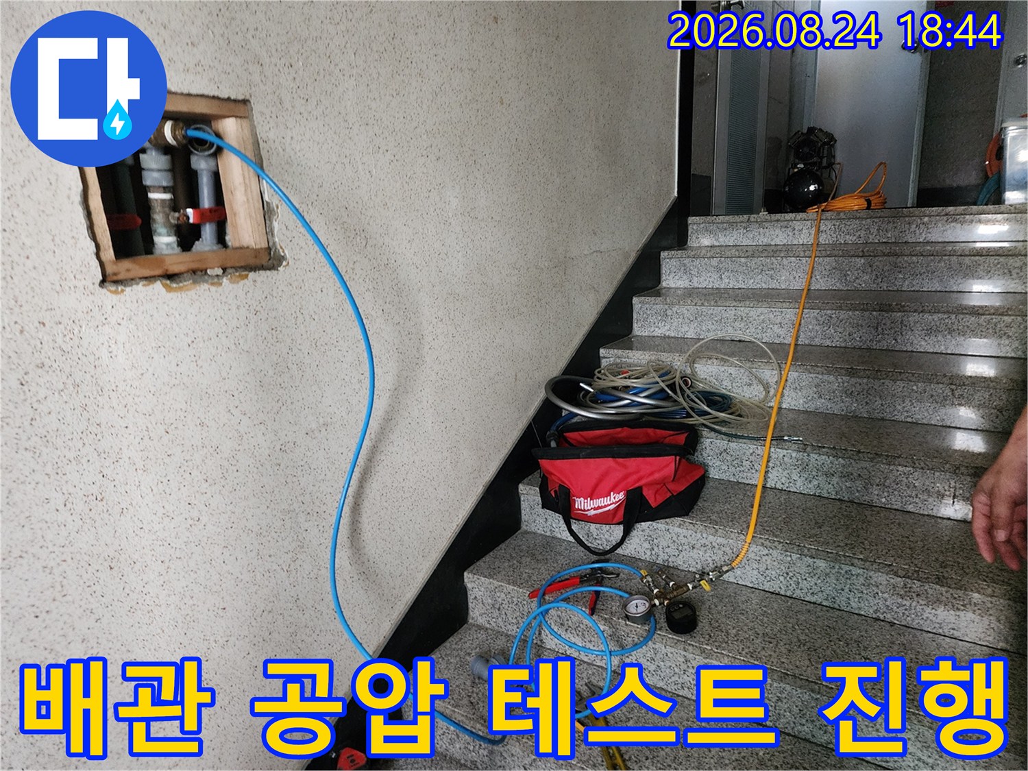 벽면 배관에 연결된 파란색 호스와 압력 측정 장비의 배치 상태