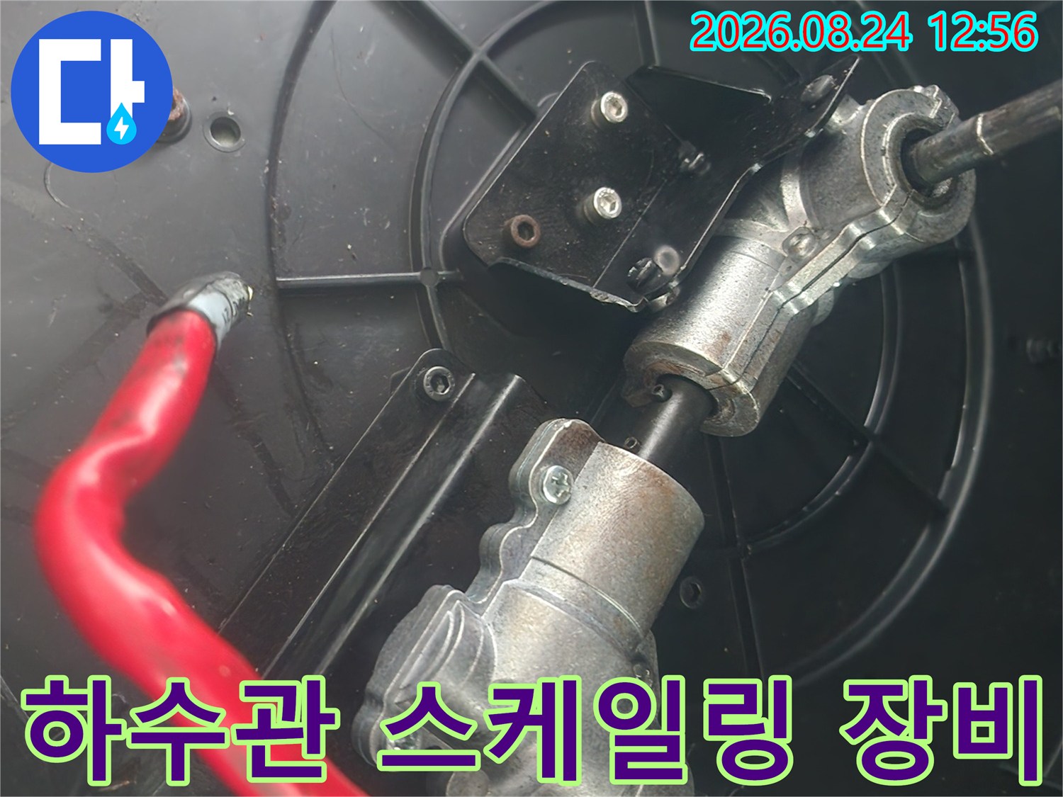 금속 샤프트와 빨간색 호스가 연결되어 배관에 설치된 모습