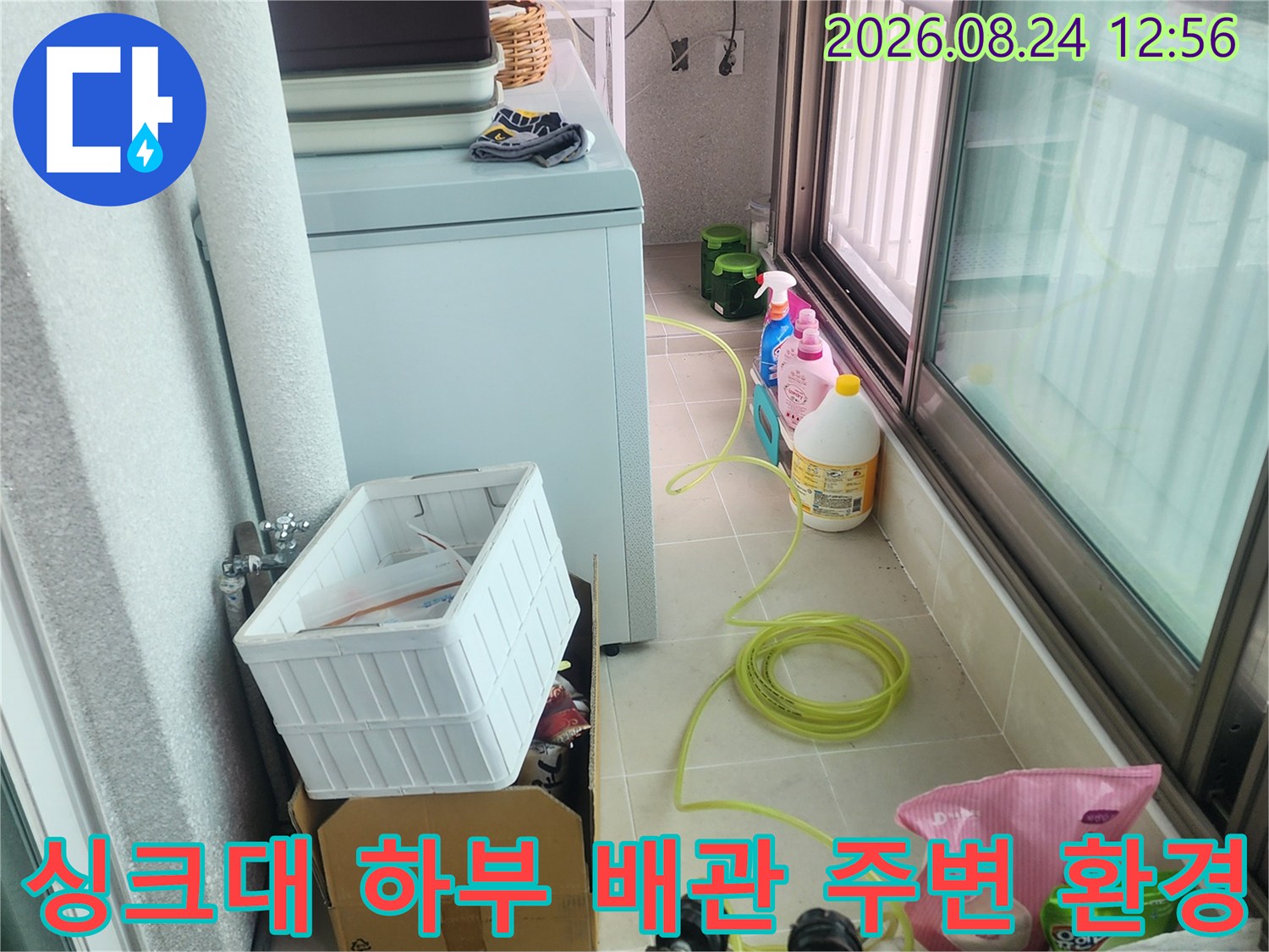 싱크대 아래쪽의 배관 구조와 작업 도구가 놓여 있는 현장 모습입니다.