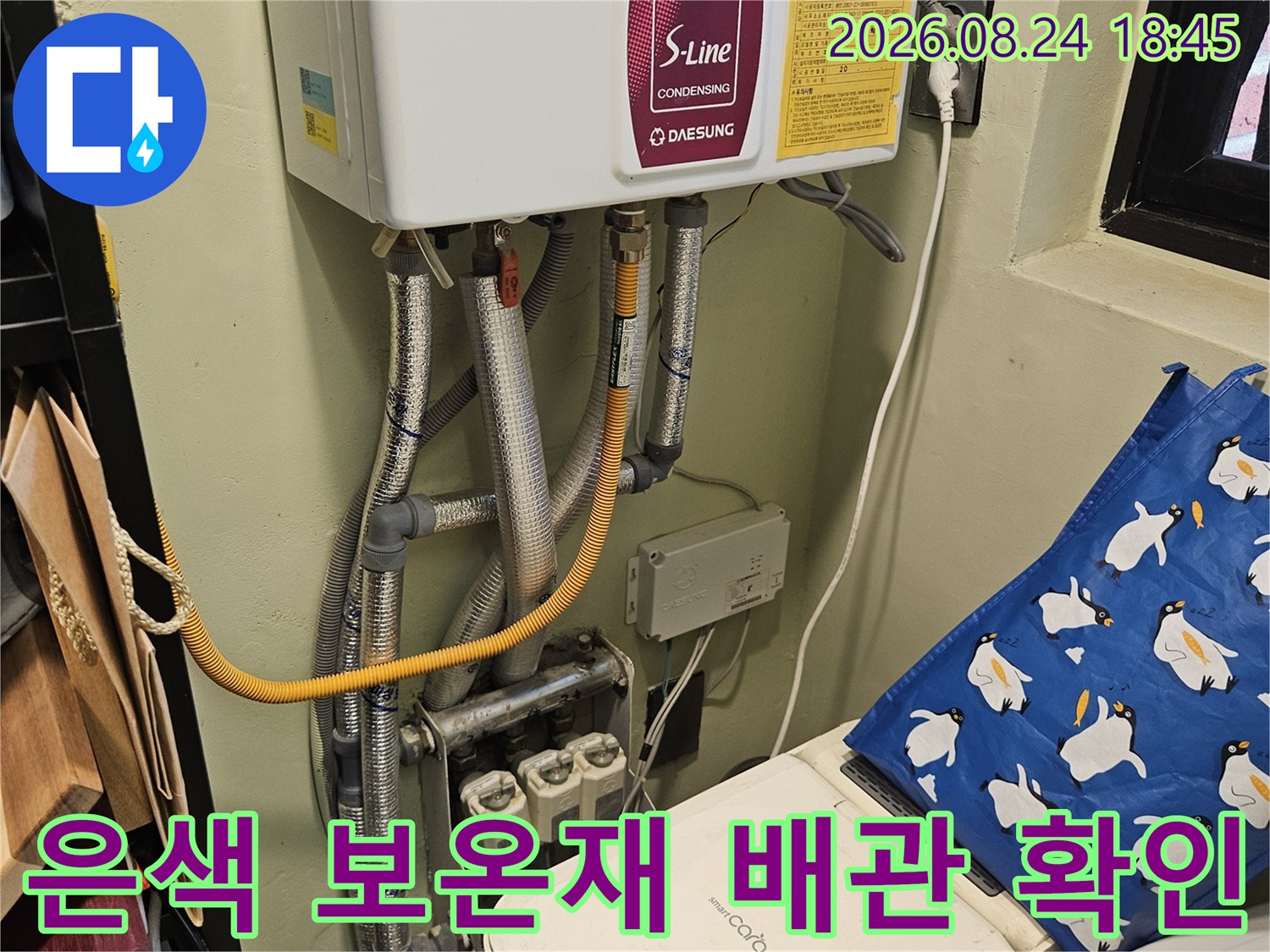 보일러 아래 설치된 은색 보온재와 노란색 호스 연결 부위