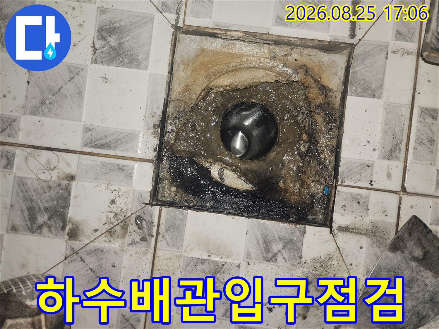 오염된 배관 입구와 주변 타일의 변색 상태를 촬영한 사진입니다.