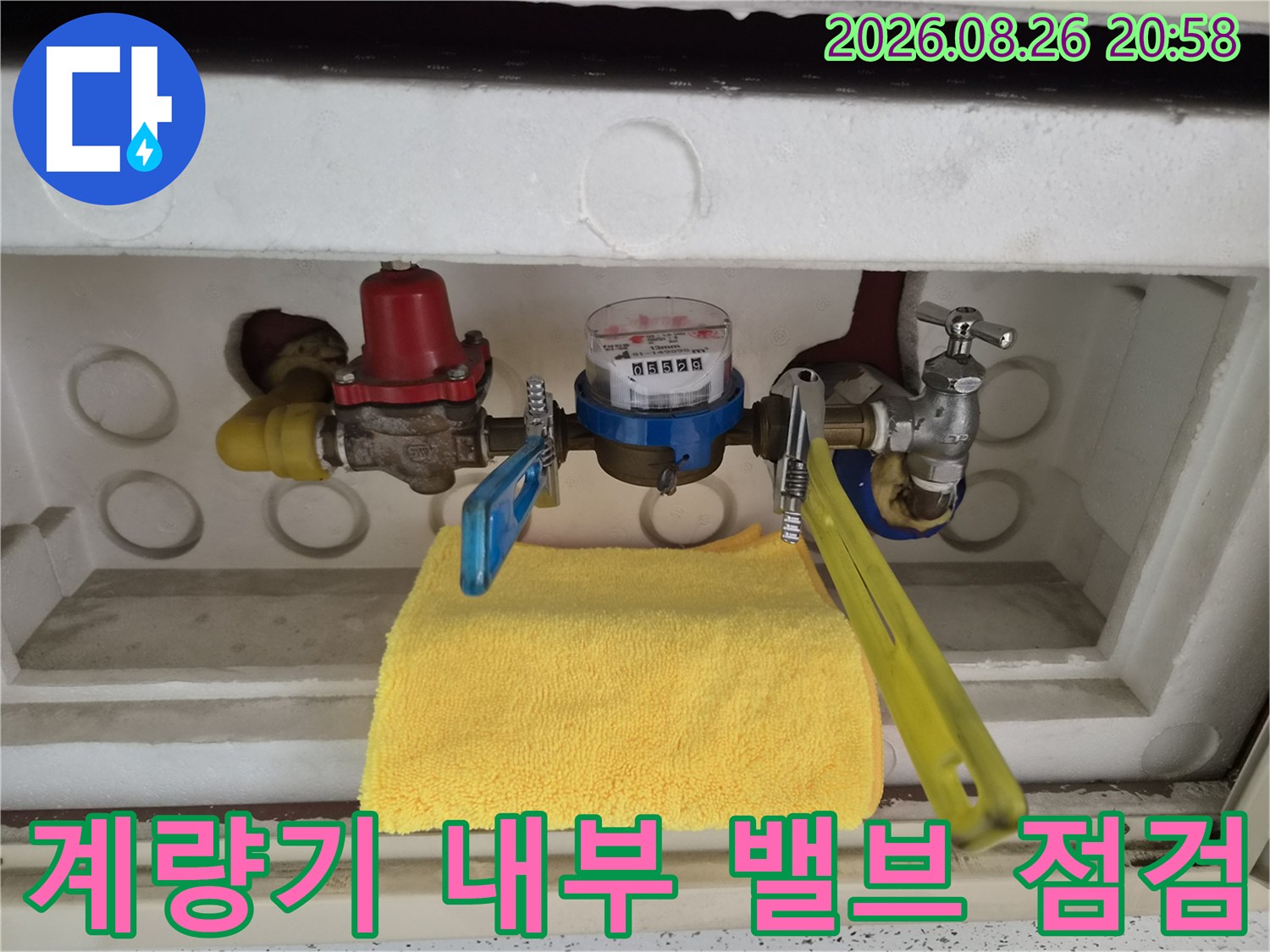 수도 계량기와 파란색 핸들 및 빨간색 부품의 모습입니다.