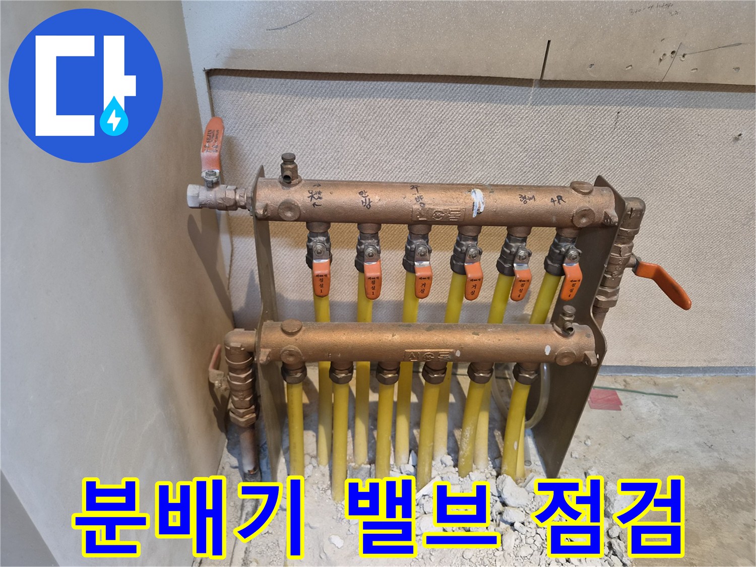 주황색 손잡이가 달린 밸브와 노란색 배관이 연결된 모습입니다.