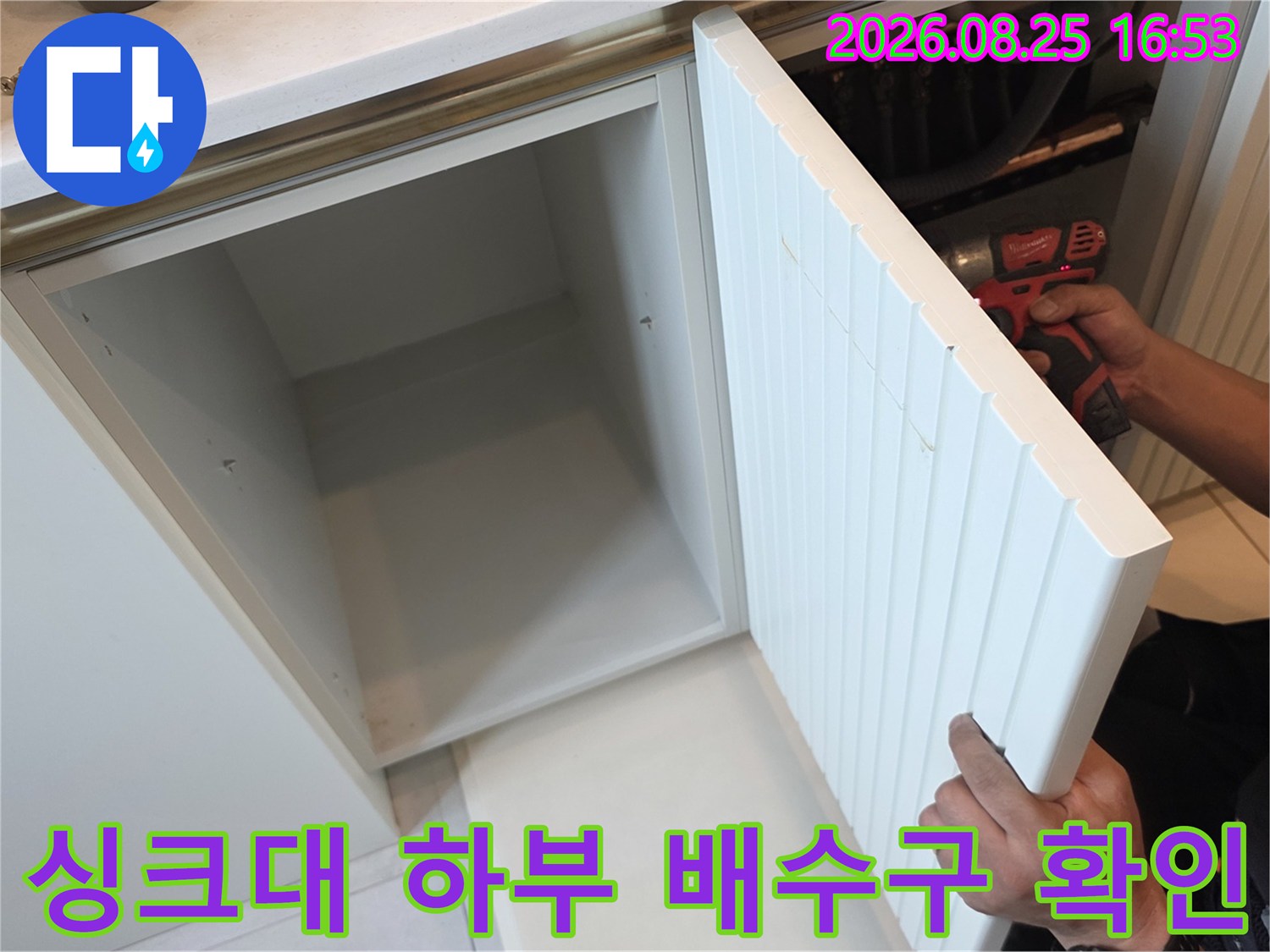 열린 싱크대 하부장 내부의 배관 연결 부위를 엔지니어가 점검하고 있습니다.