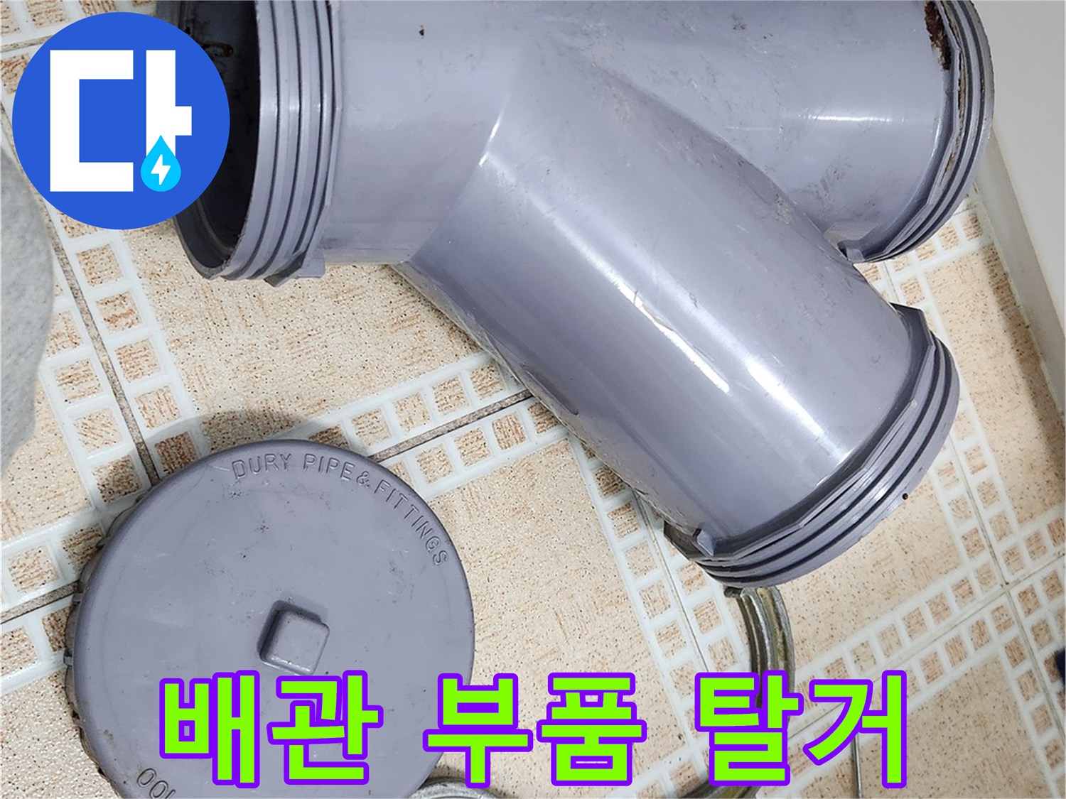 분리된 오수관 부속과 작업용 클램프가 놓인 모습입니다.